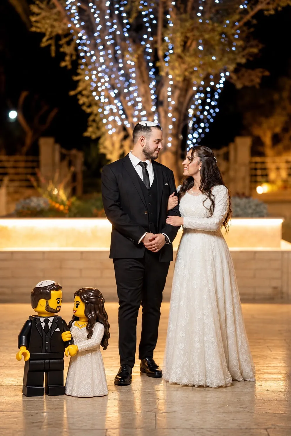 חתן וכלה בלילה תחת עץ מואר ולידם דמויות לגו של חתן וכלה